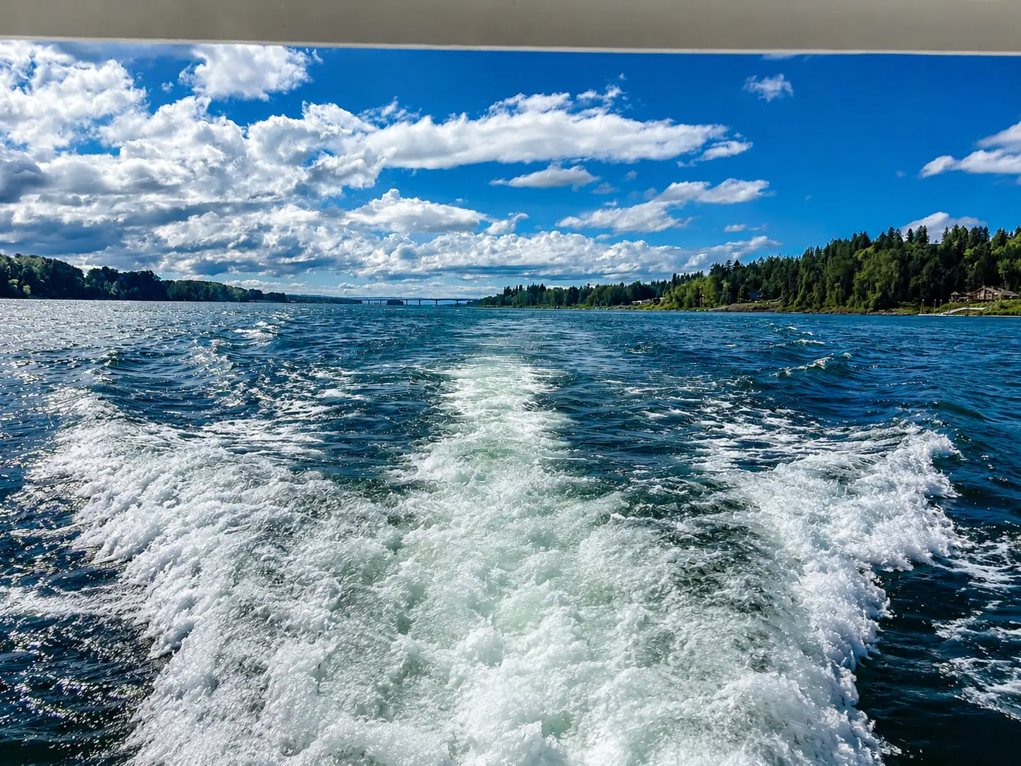 Wake trailing astern under a big cloud sky
