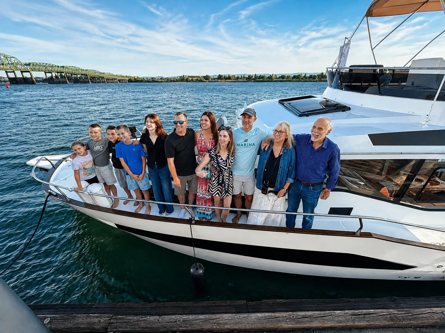 Multi generation family on the bow at the dock with a bridge behind